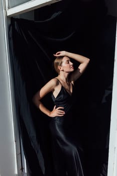 Portrait of a beautiful young woman in a black silk evening dress