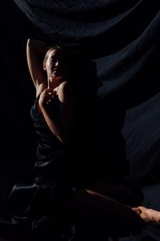 Portrait of a beautiful young woman in a black silk evening dress