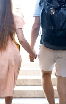 couple holding hands walking through the city