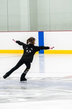Little girl practicing figure skating at the indoor ice rink.
