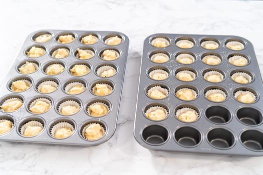 Scooping cupcake batter with dough scoop into a baking pan with liners to bake American flag mini cupcakes.