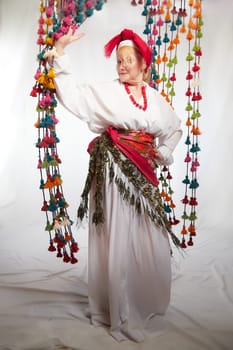 Portrait of cheerful funny adult mature woman solokha. Female model in clothes of national ethnic Slavic style. A stylized Ukrainian, Belarusian or Russian woman poses in a comic photo shoot