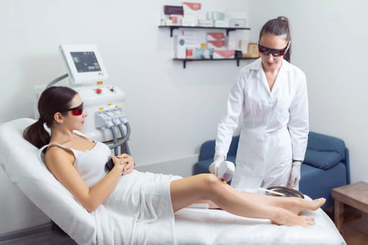 Professional beautician removes hair on beautiful female legs using a laser. hair removal on the legs, laser procedure at clinic.