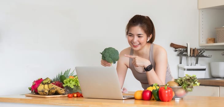 Healthy Asian woman takes care of her health by eating vegetable and fruit salad, adding vitamins in the kitchen..