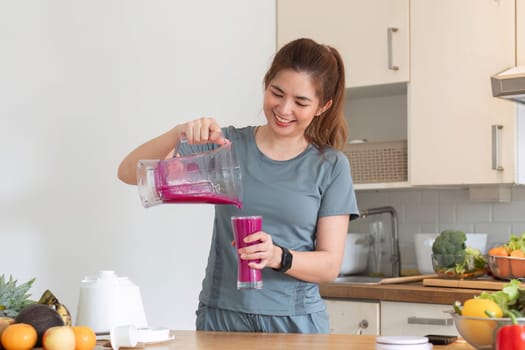 Young attractive Asian woman makes a fruit smoothie in the kitchen. Take care of your health by eating fruits and vegetables to add vitamins..