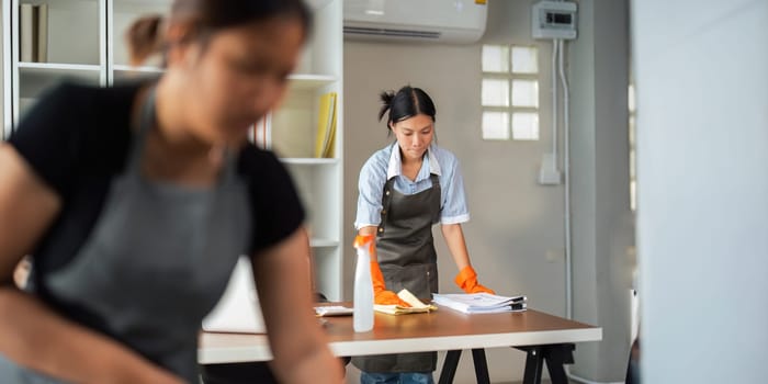 Asian woman cleaning in work room at home. Young woman housekeeper cleaner use a cloth to wipe equipment for working. concept housekeeping housework cleaning.