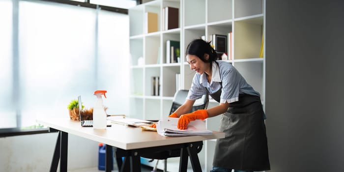 Asian woman cleaning in work room at home. Young woman housekeeper cleaner use a cloth to wipe equipment for working. concept housekeeping housework cleaning.