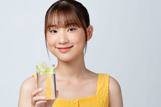 Young woman drinking cucumber water on white background