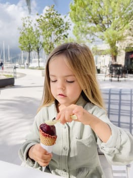 Little girl picks up popsicles in a waffle cone with a spatula. High quality photo