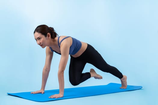 Asian woman in sportswear doing burpee on exercising mat as workout training routine. Attractive girl in pursuit of healthy lifestyle and fit body physique. Studio shot isolated background. Vigorous