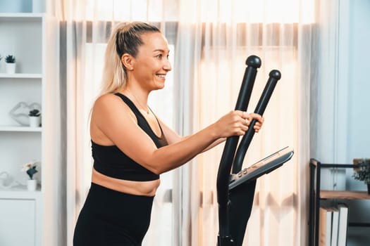 Active senior woman running on elliptical running machine at home portrait as fitness healthy lifestyle and body care after retirement for pensioner. Clout