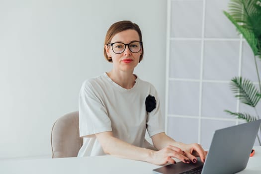 Business woman in glasses working on laptop in office