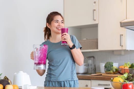 Young attractive Asian woman makes a fruit smoothie in the kitchen. Take care of your health by eating fruits and vegetables to add vitamins..