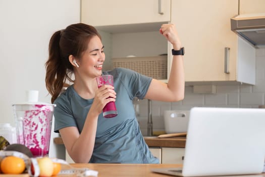 Young attractive Asian woman makes a fruit smoothie in the kitchen. Take care of your health by eating fruits and vegetables to add vitamins..