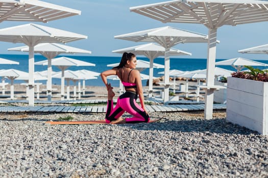 Active lifestyle. Young beautiful woman doing morning yoga on beach at sunrise, doing stretching outdoors. Concept of sports, sports training, yoga or fitness.
