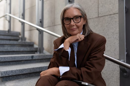 portrait of a successful well-groomed gray-haired middle-aged business woman dressed in a stylish suit in an urban environment.