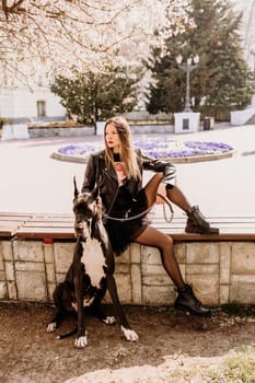 A woman walks with her Great Dane in an urban setting, enjoying the outdoors and the company of her dog