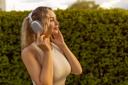 Portrait of fit girl preparing for running in workout clothes looking at camera smiling. Beautiful happy sportswoman enjoying doing sports listening to music using headphones. Music concept