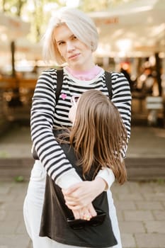 Happy young mother and little daughter are playing and fooling around outside