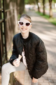 Adorable little girl eating delicious ice cream outdoors on sunny summer day, space for text