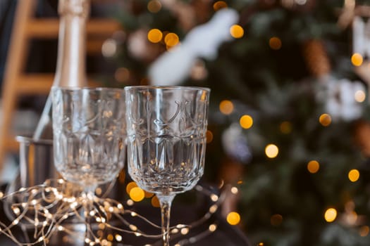 Champagne glasses, New Year decor. New Year's festive setting, family holidays.Two glasses of champagne are on the table against the background of New Year's decorated tree