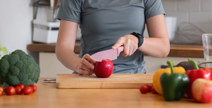 Healthy Asian woman takes care of her health by eating vegetable and fruit salad, adding vitamins in the kitchen..