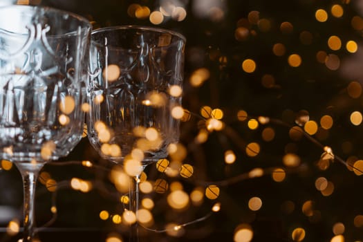 Champagne glasses, New Year decor. New Year's festive setting, family holidays.Two glasses of champagne are on the table against the background of New Year's decorated tree