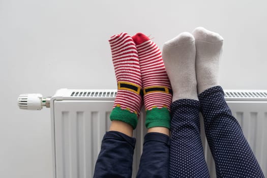 Family warming feet near heater at home, closeup.