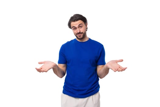 young brunette man with a beard dressed in a blue t-shirt thinks about solving problems on a white background.