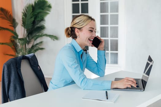 Woman talking on smartphone working on computer