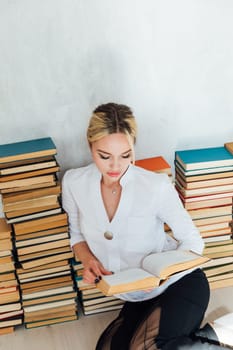 Beautiful smart woman sitting on books loves to read