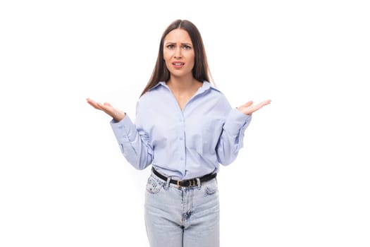 young stylish caucasian model woman with makeup and with dark straight hair dressed in a blue blouse on a white background with copy space.