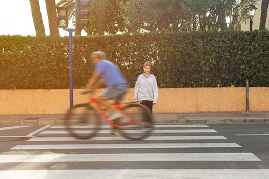 teenage girl crosses the road at a green light and rides a cyclist breaks the rules and rides in front of the girl.Traffic violation concept. High quality photo