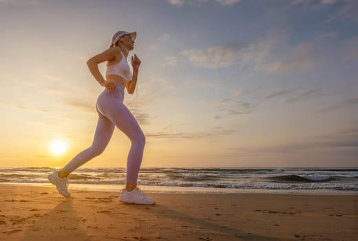 silhouette of a sports girl against the background of the sea at dawn, the girl stands in leggings and a top, in a cap against the background of the sea. High quality photo