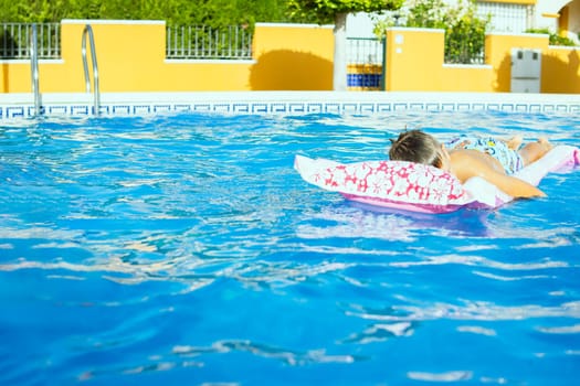 a boy of European appearance is resting on a pink inflatable mattress in the pool, there is a place for an inscription. Summer holiday concept. High quality photo