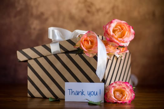 gift box with ribbons and beautiful roses inside, on a wooden table.
