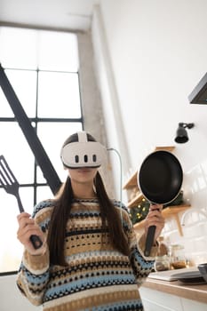 The young and beautiful woman is preparing food in the kitchen using a virtual reality headset. High quality photo