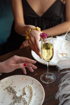 close-up of women's hands reaching for a glass of wine.