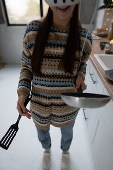 Using a virtual reality headset, the young and beautiful woman cooks in the kitchen. High quality photo