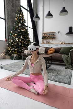 Practicing yoga, the girl dons pink sports clothing and virtual reality glasses. High quality photo