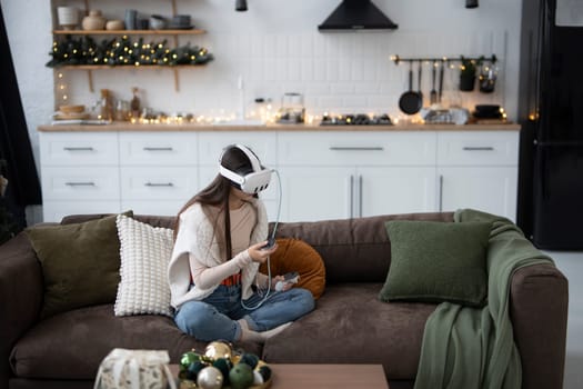 In a cozy holiday ambiance at home, a fashionable young lady uses a virtual reality headset. High quality photo