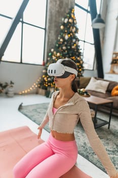 Utilizing a virtual reality headset, the yoga coach conducts online sessions amidst the New Year holidays. High quality photo