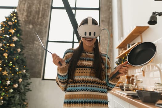 In the kitchen, a lovely young lady cooks while donning a virtual reality headset. High quality photo