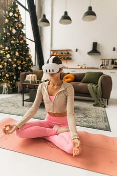 A woman in pink sportswear practices yoga with virtual reality glasses. High quality photo