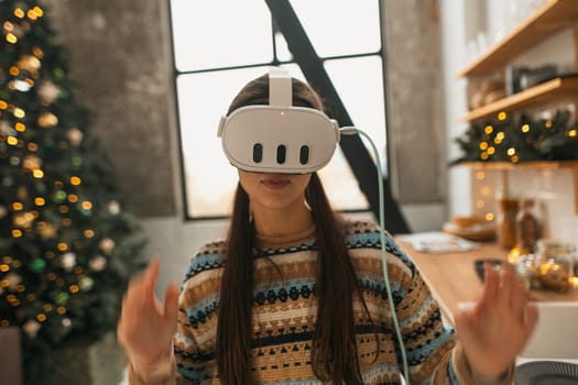 Utilizing a virtual reality headset, a beautiful and stylish girl prepares a Christmas recipe in the kitchen. High quality photo