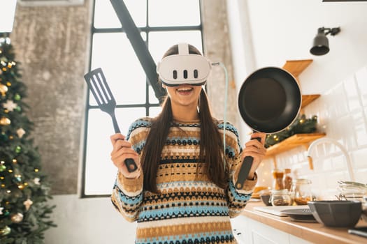 Using a virtual reality headset, a young and beautiful woman prepares food in the kitchen. High quality photo