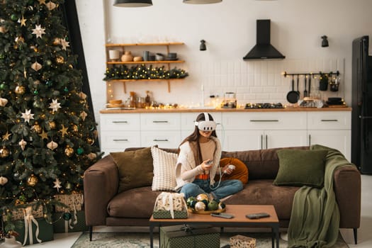Embraced by a cozy Christmas setting at home, a fashionable young lady wears a virtual reality headset. High quality photo