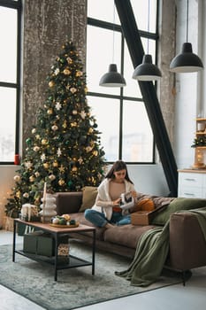Amidst a warm Christmas ambiance at her place, a stylish young woman is seen in a virtual reality headset. High quality photo