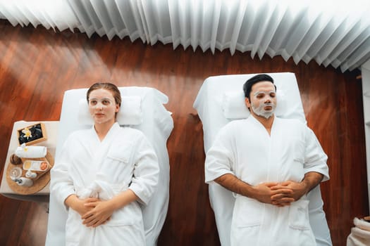 Serene modern daylight ambiance of spa salon, couple customer indulges in rejuvenating with facial skincare mask. Facial skin treatment and beauty cosmetology procedure for face. Quiescent