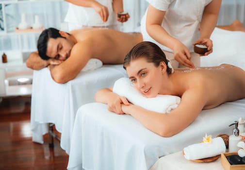 Woman customer having exfoliation treatment in luxury spa salon with warmth candle light ambient. Salt scrub beauty treatment in health spa body scrub. Quiescent